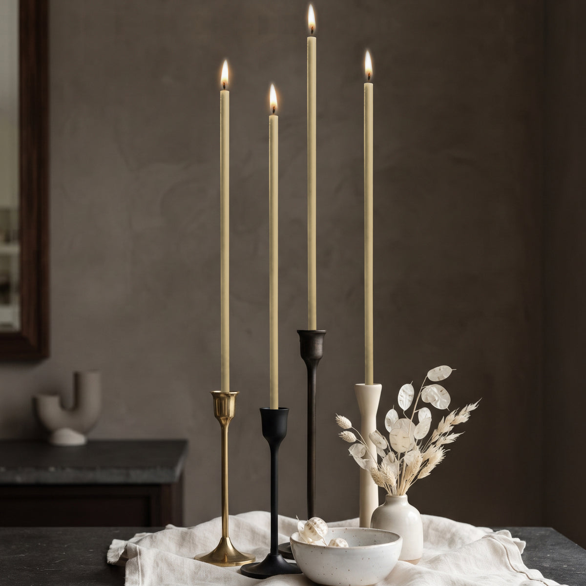 White beeswax taper candles 10.4″, lit in mixed candlesticks