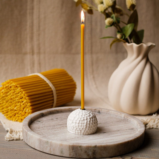 Natural thin beeswax candle in a holder
