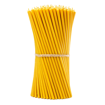 "Bundle of pure beeswax taper candles tied with twine on a white background"