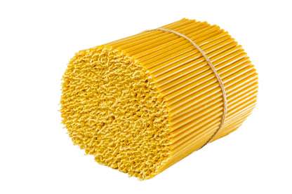 Large bundle of thin beeswax taper candles tied with twine on a white background.