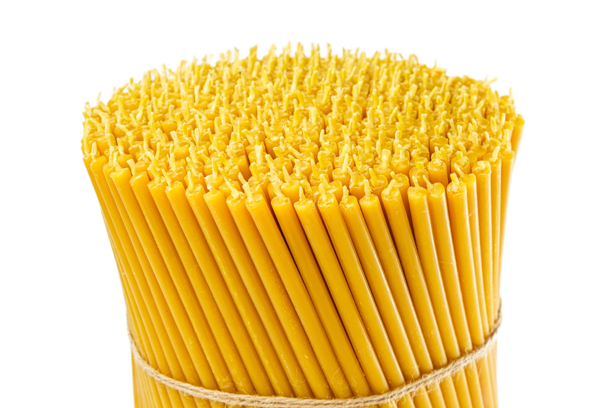 Close-up of a large bundle of thin beeswax taper candles tied with twine on a white background.