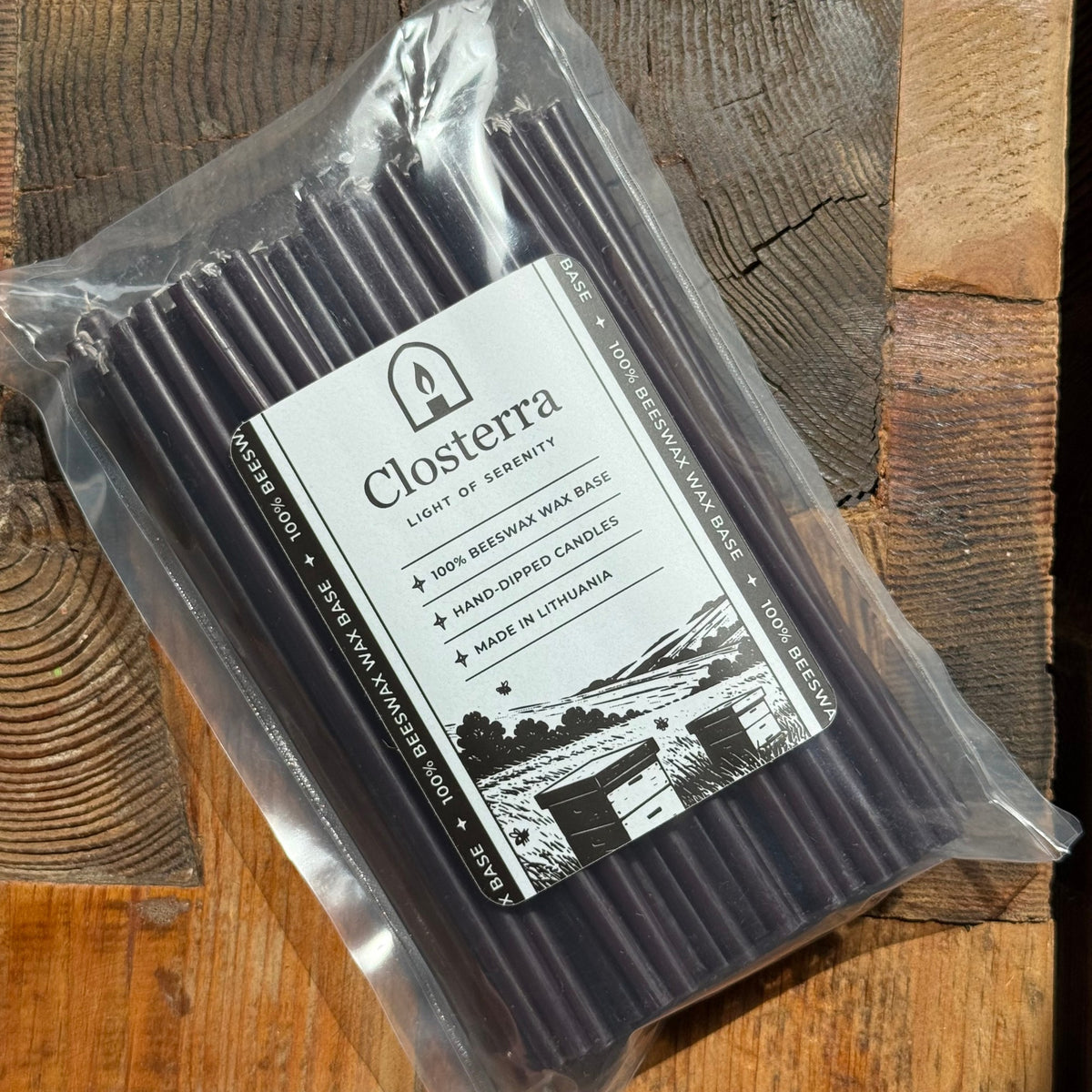Black beeswax taper candles 6.3″, in packaging on rustic wood