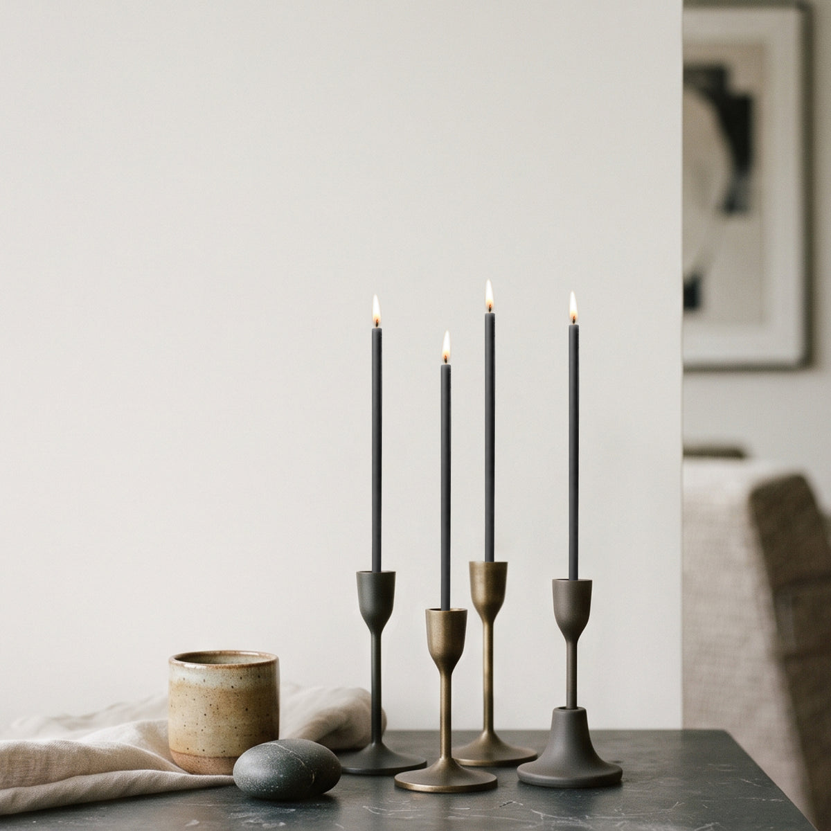 Black beeswax taper candles 6.5″, lit in brass candlesticks