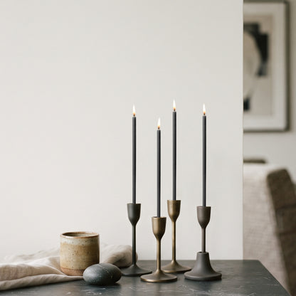 Black beeswax taper candles 6.5″, lit in brass candlesticks