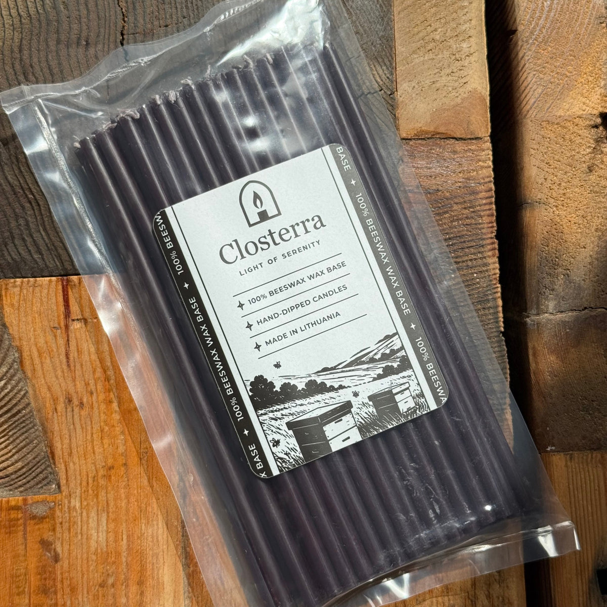 Black beeswax taper candles 7.3″, in packaging on wood planks