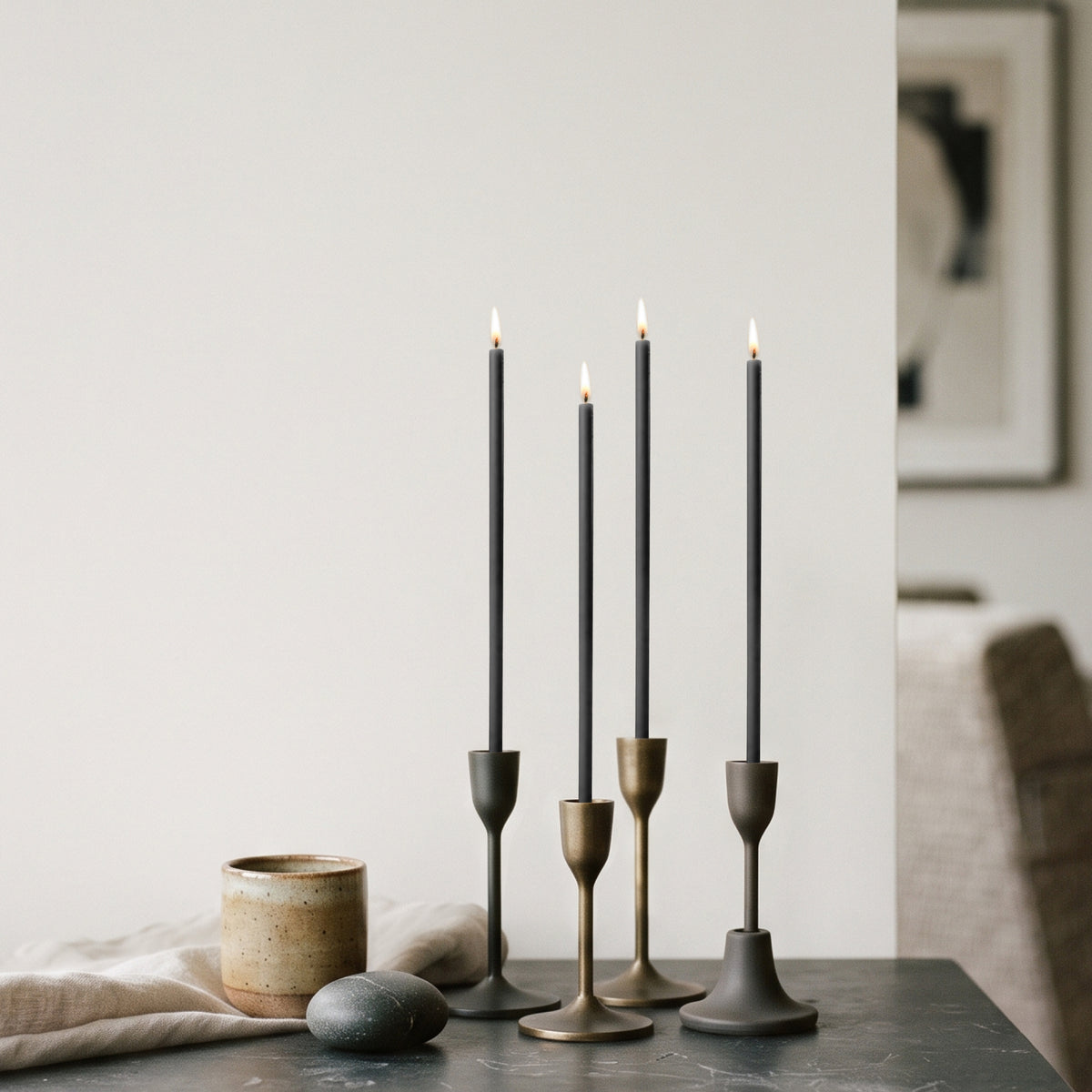 Black beeswax taper candles 7.3″, lit in brass candlesticks