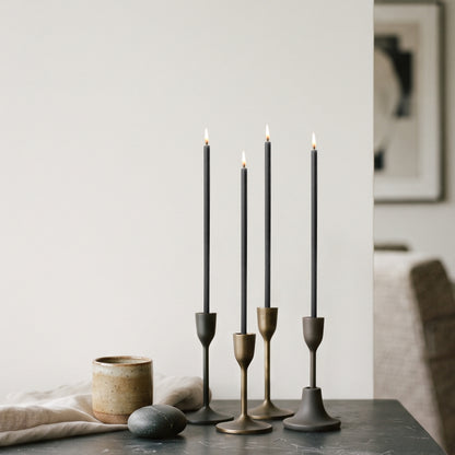 Black beeswax taper candles 7.3″, lit in brass candlesticks