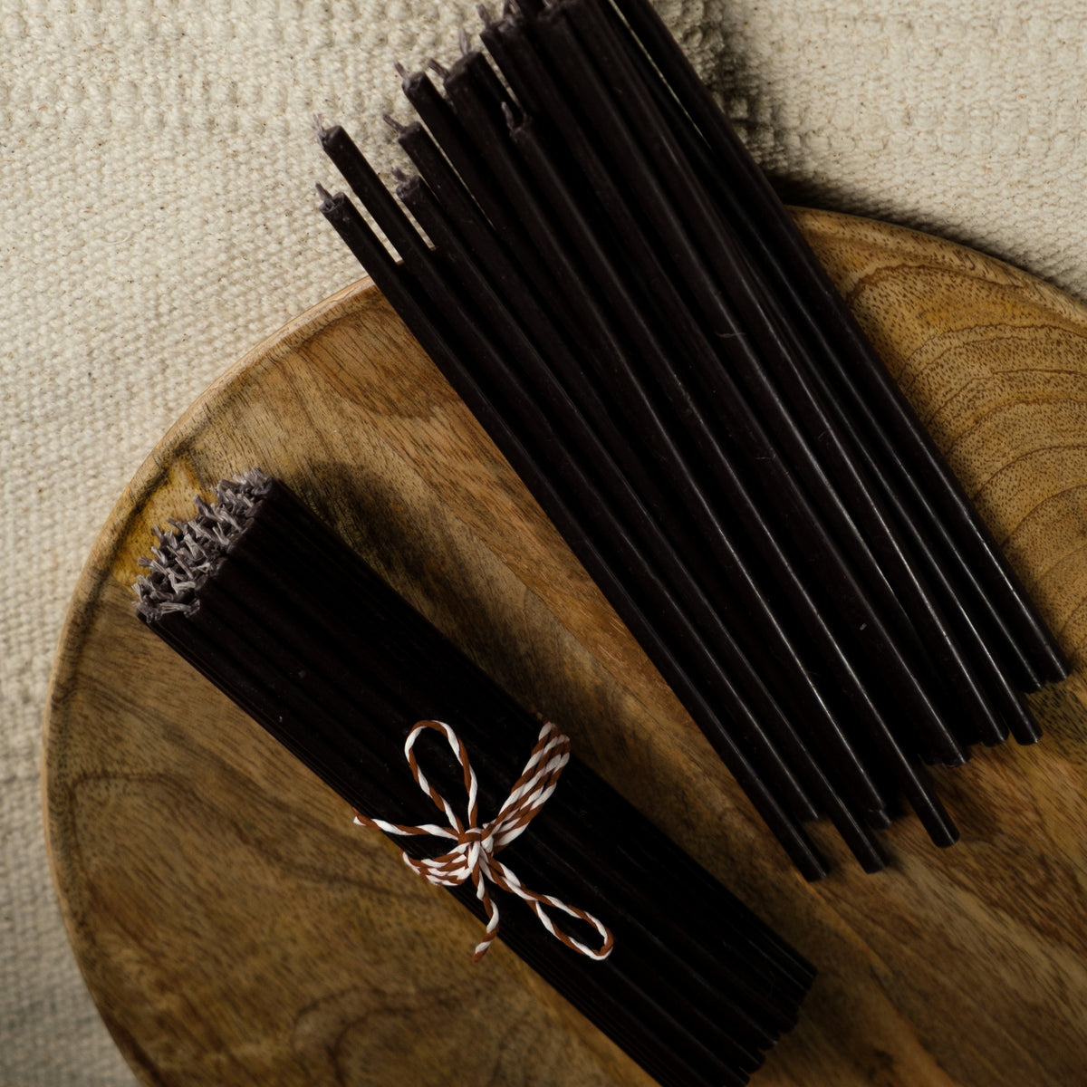 Black beeswax taper candles 6.3″, bundle tied with twine on a wooden tray