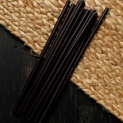 Black beeswax taper candles 7.3″, loose tapers on dark wood and a jute mat