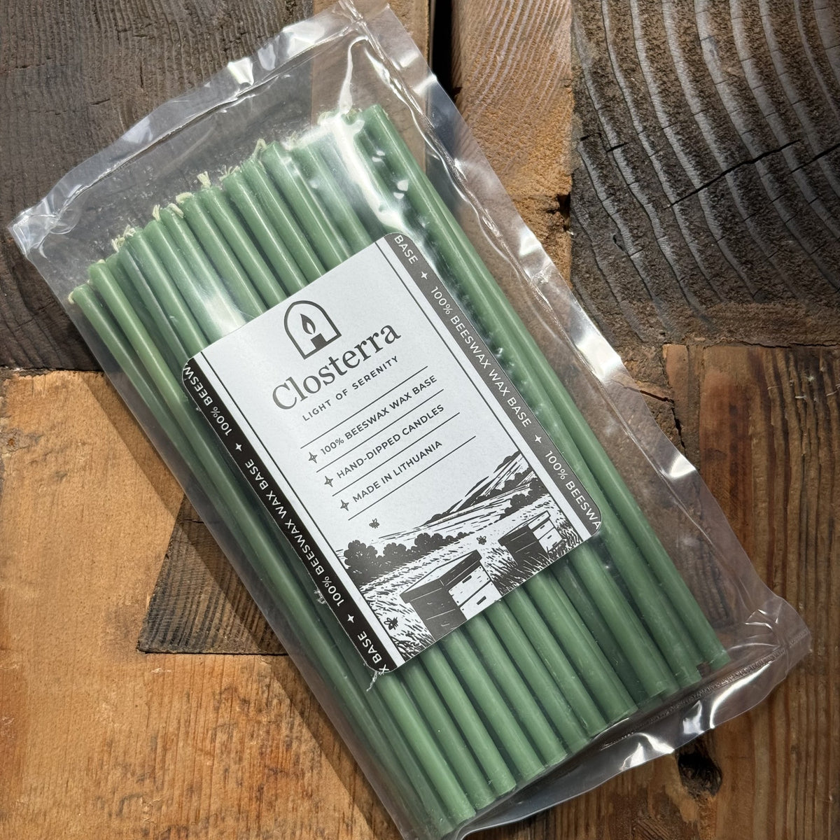 Green beeswax taper candles 7.3″, in Closterra packaging on rustic wood