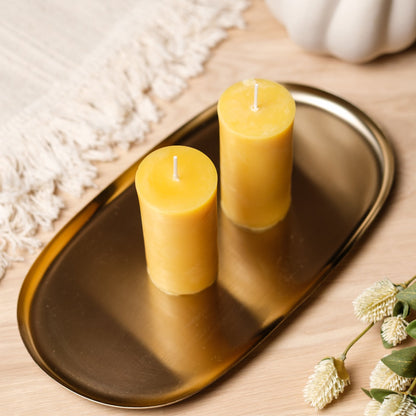 Natural beeswax pillar candle on a gold tray