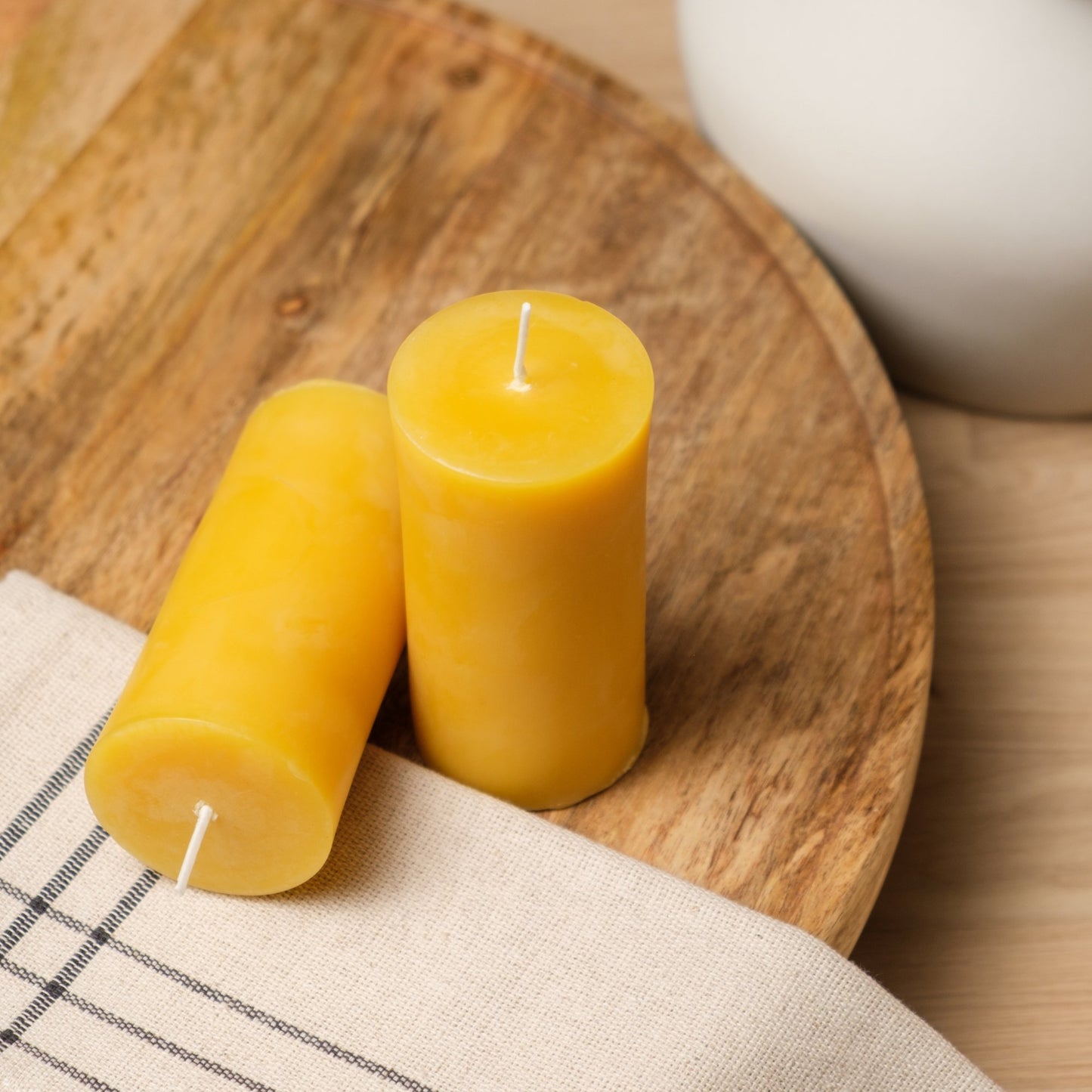 Natural beeswax pillar candle, 2 by 4 inch, on a rustic wooden board