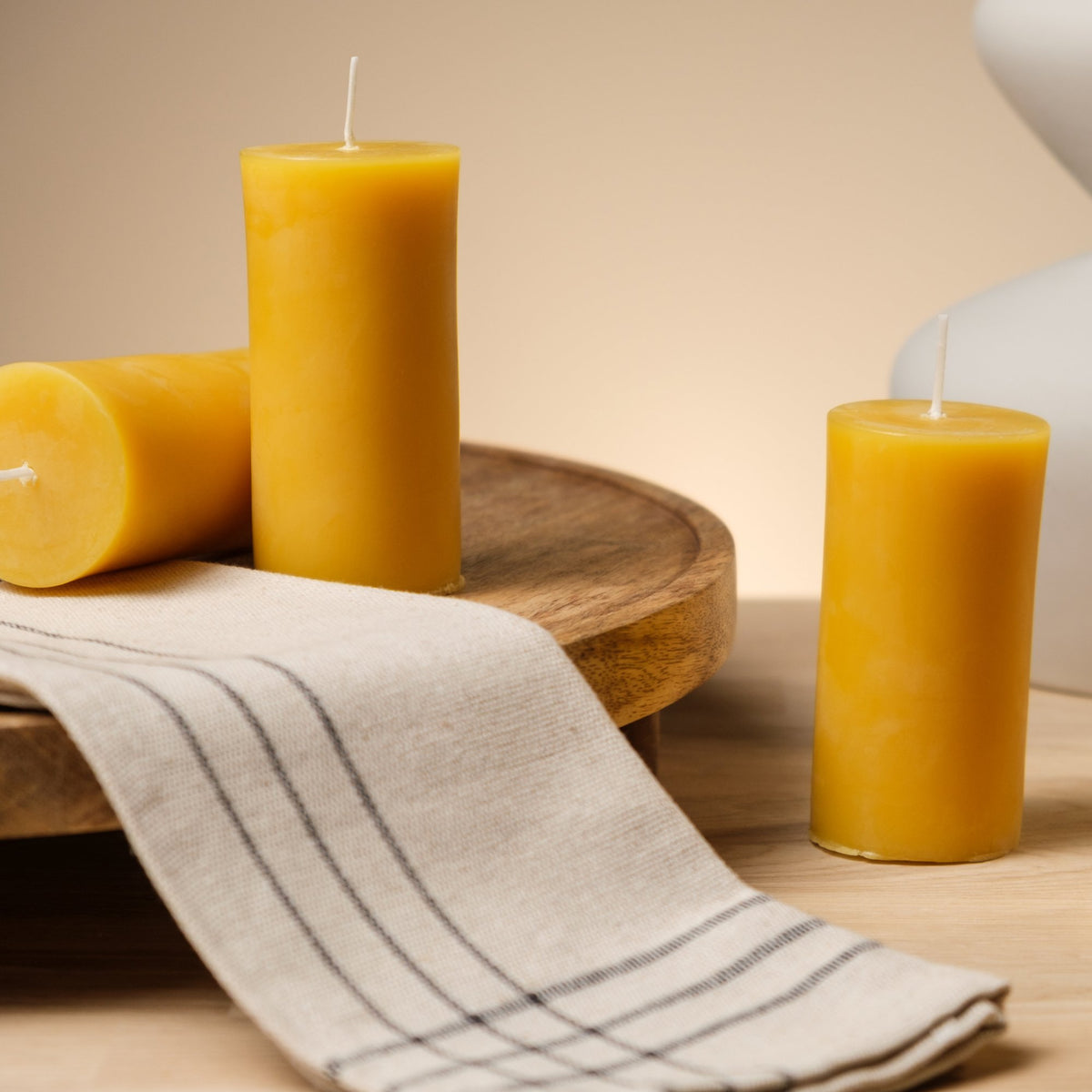Natural beeswax pillar candle on a wooden stand