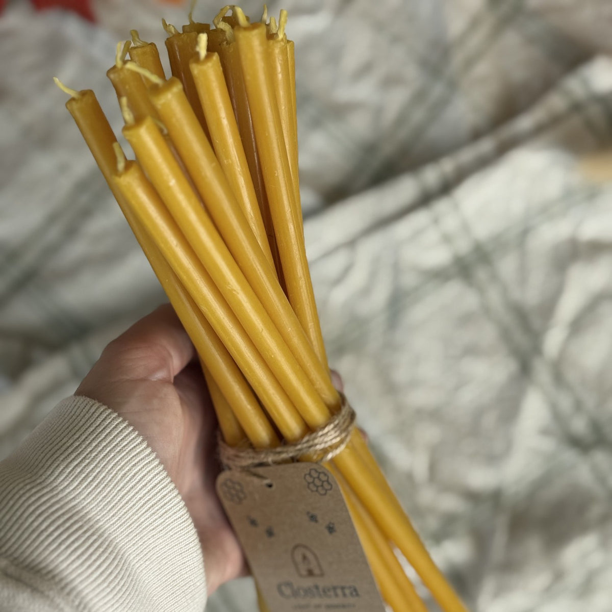 Natural yellow beeswax taper candles 11.6″, bundle of 20 held in hand
