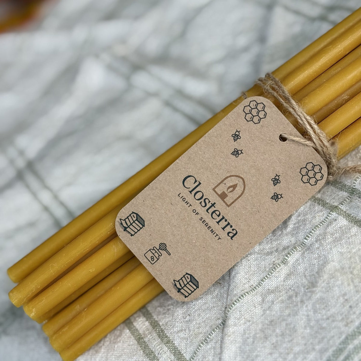 Natural yellow beeswax taper candles 11.6″, bundle of 25 with Closterra tag on linen