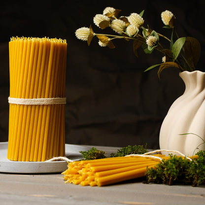Natural yellow beeswax taper candles 11.6″, bundle beside a white vase and dried flowers