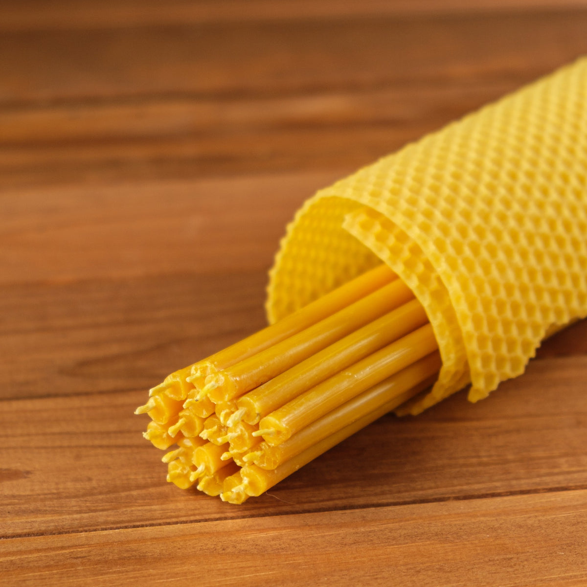 Natural yellow beeswax taper candles 11.6″, bundle wrapped in a honeycomb sheet on wood