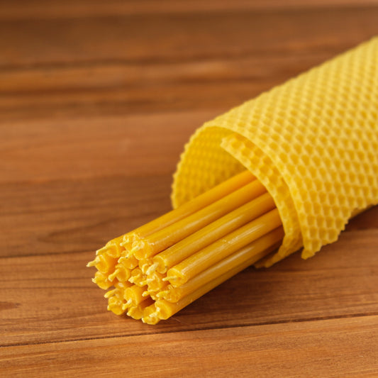 Natural yellow beeswax taper candles 11.6″, bundle wrapped in a honeycomb sheet on wood