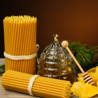 Natural yellow beeswax taper candles 6.5″, bundles beside a honey jar and beeswax pieces