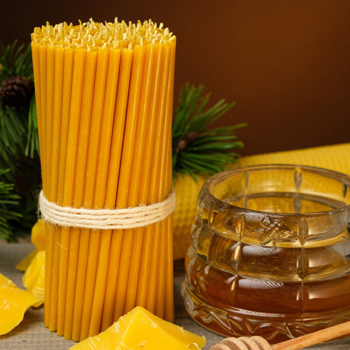 Natural yellow beeswax taper candles 7.3″, bundle beside a honey jar and beeswax pieces