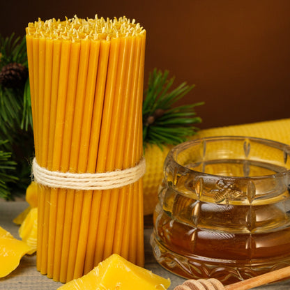 Natural yellow beeswax taper candles 7.3″, bundle beside a honey jar and beeswax pieces
