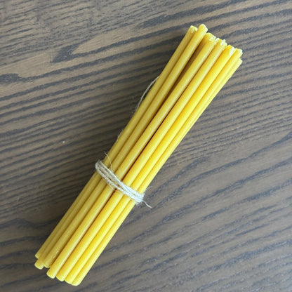 Natural yellow beeswax taper candles 8″, bundle of 20 tied with twine on wood