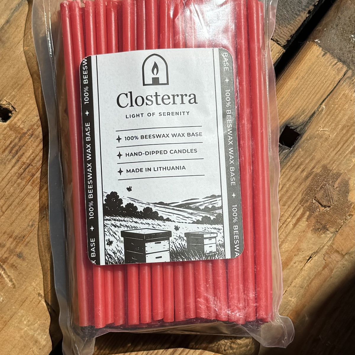 Red beeswax taper candles 6.3″, in Closterra packaging on rustic wood