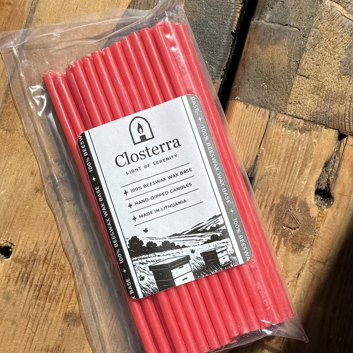 Red beeswax taper candles 7.3″, in Closterra packaging on rustic wood, close-up