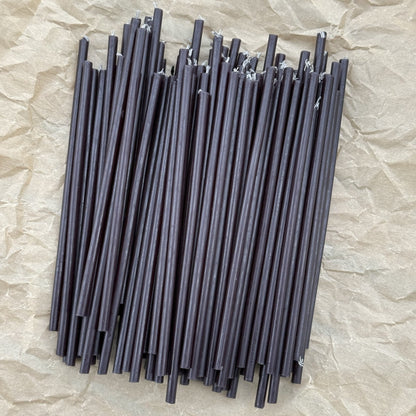 Loose thin black beeswax ritual candles on crinkled kraft paper
