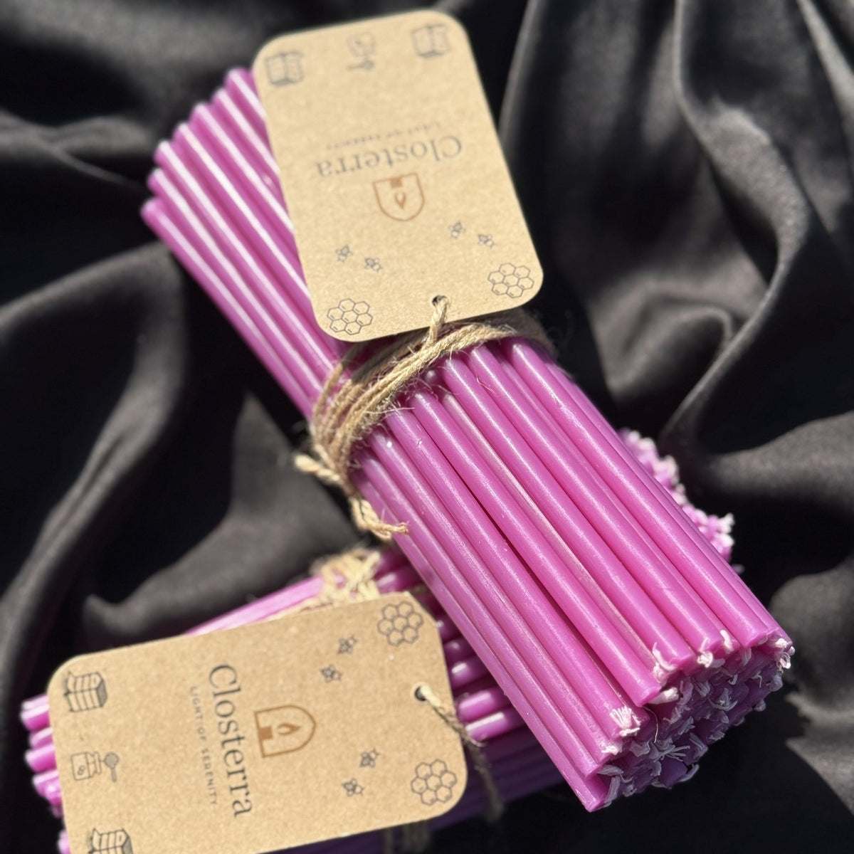 Two bundles of purple beeswax ritual candles tied with twine and Closterra tags