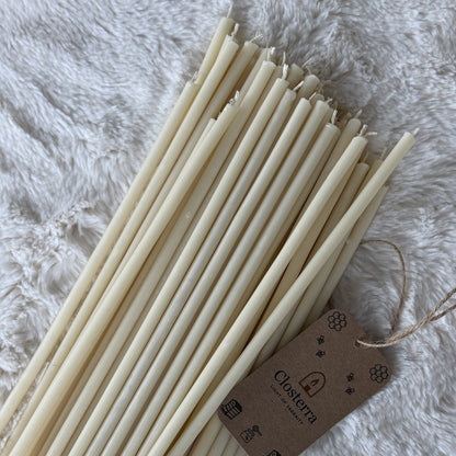 Long white beeswax ritual candles with a Closterra tag on white faux fur