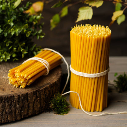Closterra thin natural yellow beeswax taper candles, on a wood slice