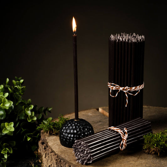 Closterra thin black beeswax taper candles, lit and styled on a table
