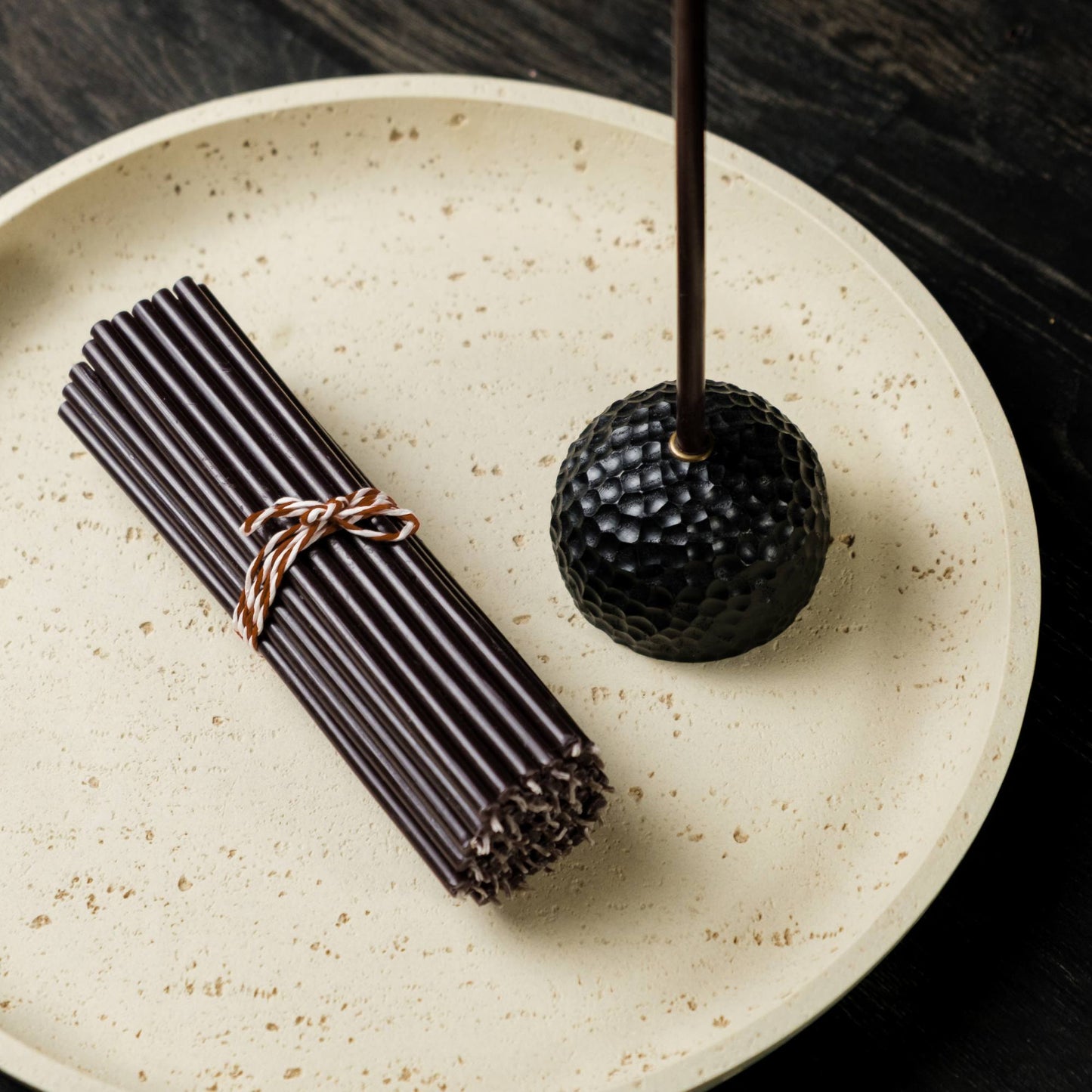 Closterra thin black beeswax taper candles, on a plate