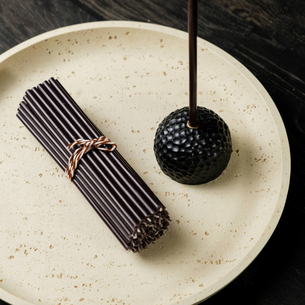 Closterra thin black beeswax taper candles, on a plate