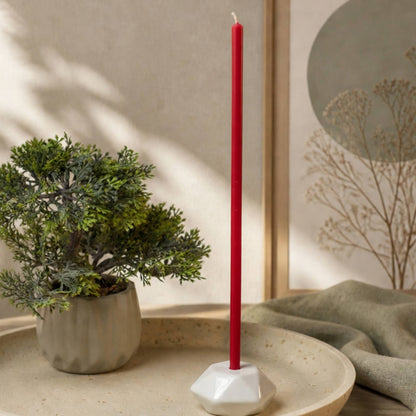 Closterra thin red beeswax taper candles, lit in a candle holder
