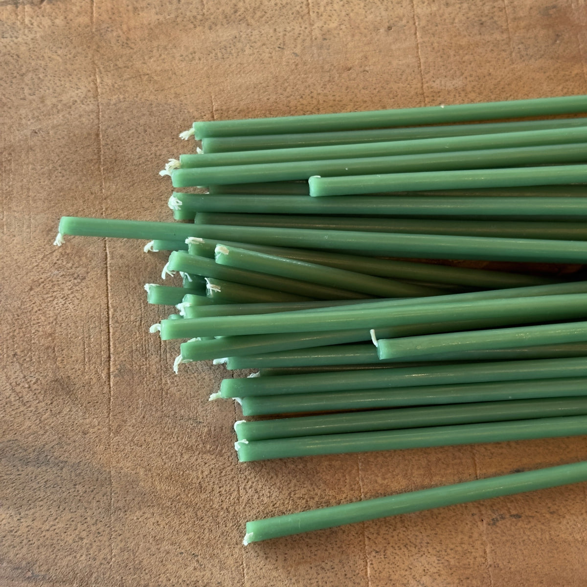 Green beeswax taper candles 6.3″, loose bundle on wood board