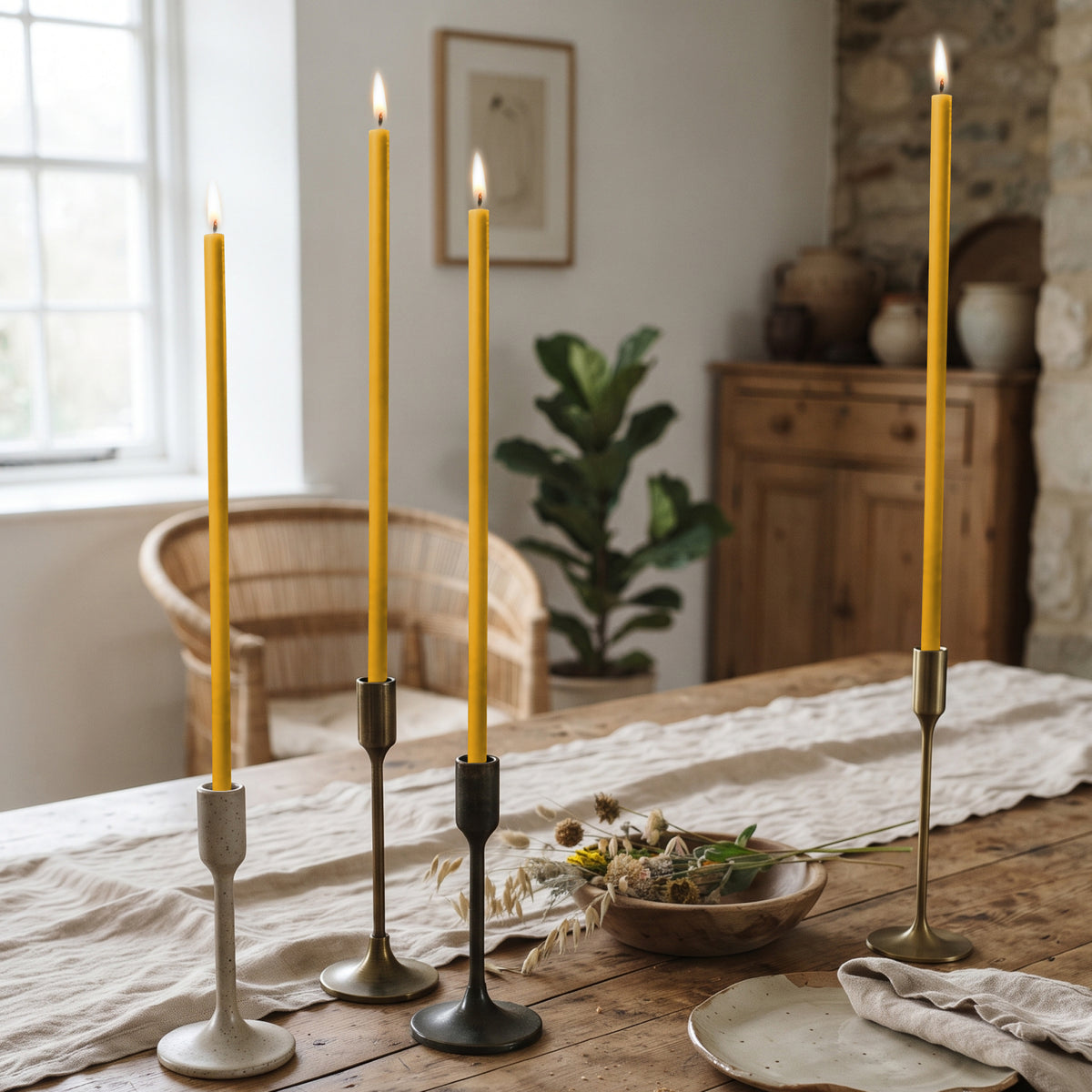 Natural beeswax taper candles 11.6″, lit in candlesticks on table