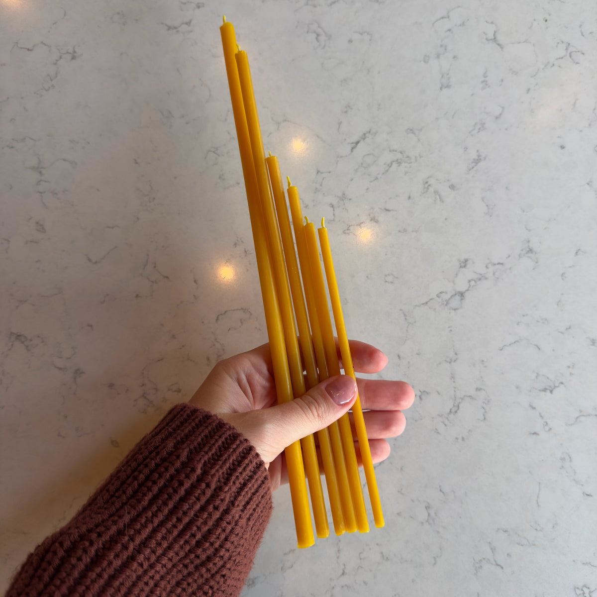 Natural beeswax taper candles 7.3″, held in hand