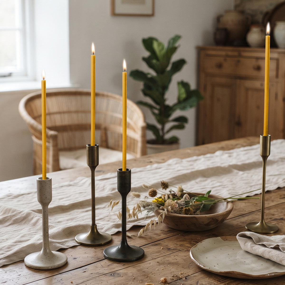 Natural beeswax taper candles 7.3″, lit in candlesticks on table