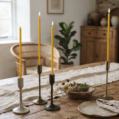 Natural beeswax taper candles 8″, lit in candlesticks on table