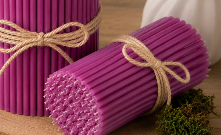 Purple thin beeswax taper candles on a wood slice, Closterra