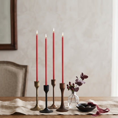 Red beeswax taper candles 7.3″, lit in mixed candlesticks