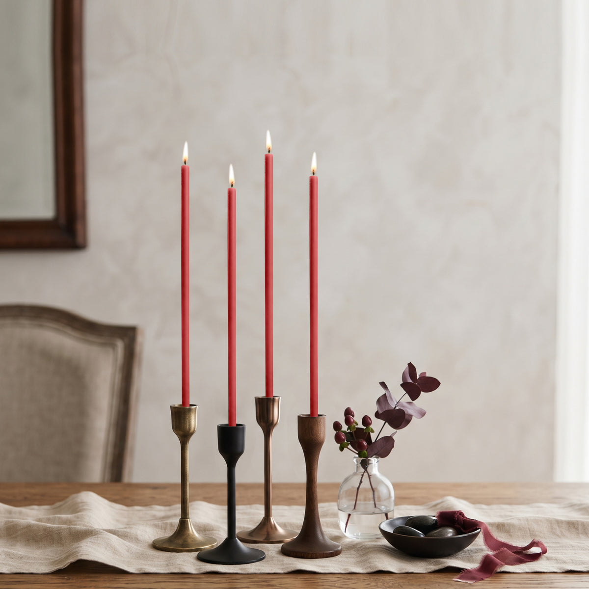 Red beeswax taper candles 8″, lit in mixed candlesticks