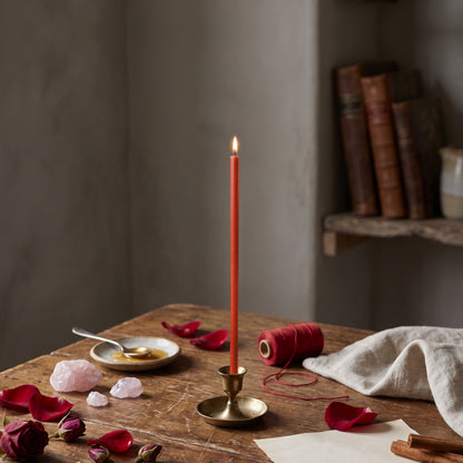 Red thin beeswax ritual candle for Love & Attraction, 7.3 inch, lit in a brass holder with rose petals, rose quartz, honey and red thread, Closterra