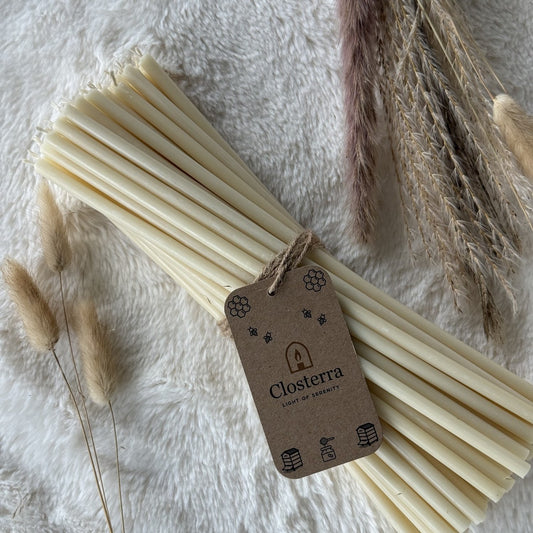 White beeswax taper candles 10.4″, bundle of 50 with Closterra tag on white fur with dried grass