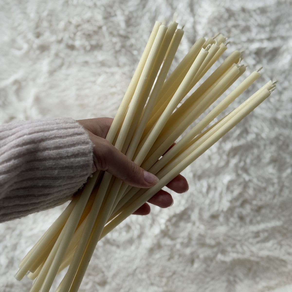White beeswax taper candles 10.4″, handful of tapers over white fur