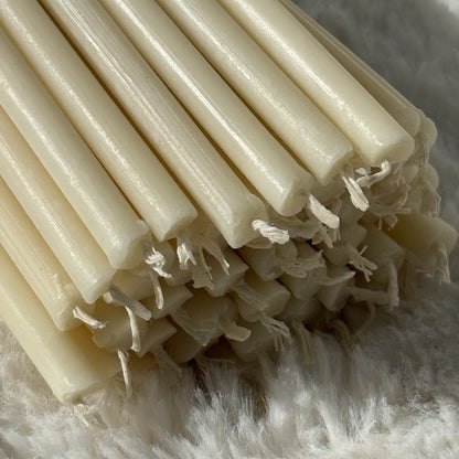 White beeswax taper candles 10.4″, wick ends closeup on white fur
