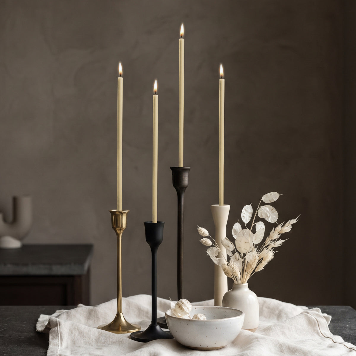 White beeswax taper candles 6.5″, lit in mixed candlesticks